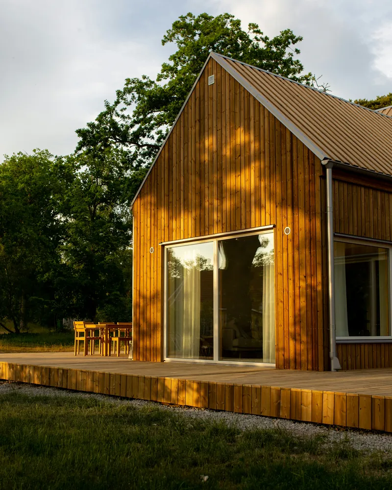 Nytt trehus med saltak, stående kledning, store glassdører og terrasse.
